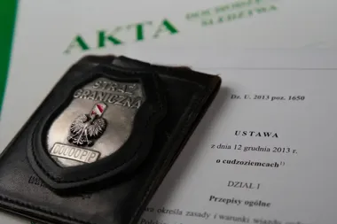 Odznaka Straży Granicznej leży na otwartej ustawie o cudzoziemcach z dnia 12 grudnia 2013 r.